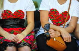 Dwie panie siedzą w białych koszulkach z naszytym czerwonym sercem w kwiaty